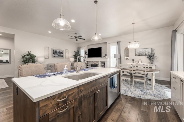 kitchen featuring dark wood finished floors, open floor plan, stainless steel dishwasher, and a sink