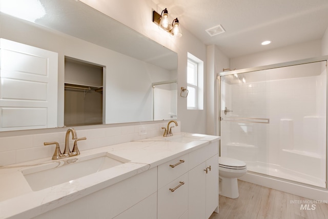 bathroom featuring a shower stall, visible vents, a walk in closet, and a sink