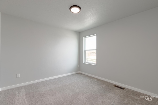 empty room with visible vents, light carpet, baseboards, and a textured ceiling