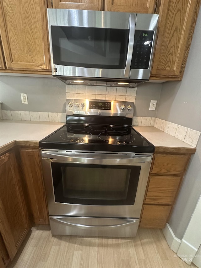 16928 N Chelford Loop, Nampa, ID 83687 - kitchen featuring appliances with stainless steel finishes, tasteful backsplash, and brown cabinetry