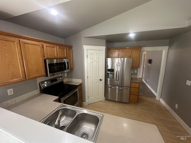 16928 N Chelford Loop, Nampa, ID 83687 - kitchen with appliances with stainless steel finishes, vaulted ceiling, brown cabinetry, light wood-type flooring, and baseboards