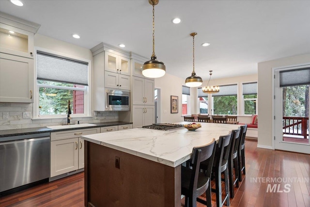 kitchen with a center island, dark stone counters, sink, white cabinetry, and stainless steel appliances