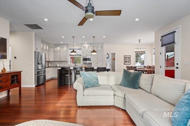 living room featuring ceiling fan and dark wood-type flooring