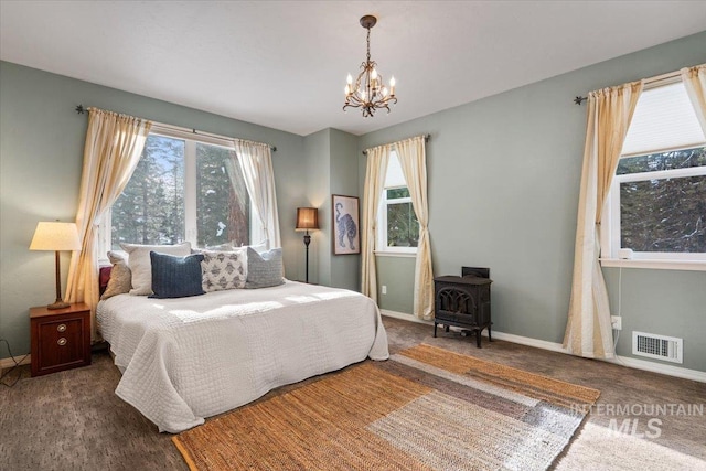 carpeted bedroom with a wood stove and a notable chandelier