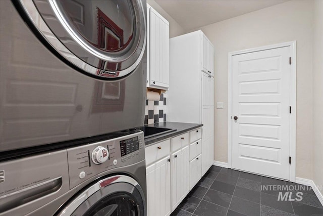 laundry area with cabinets and stacked washing maching and dryer