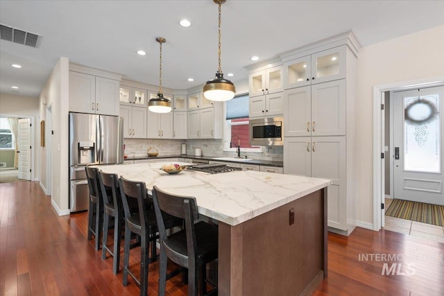 kitchen featuring decorative backsplash, a center island, stainless steel appliances, and light stone counters