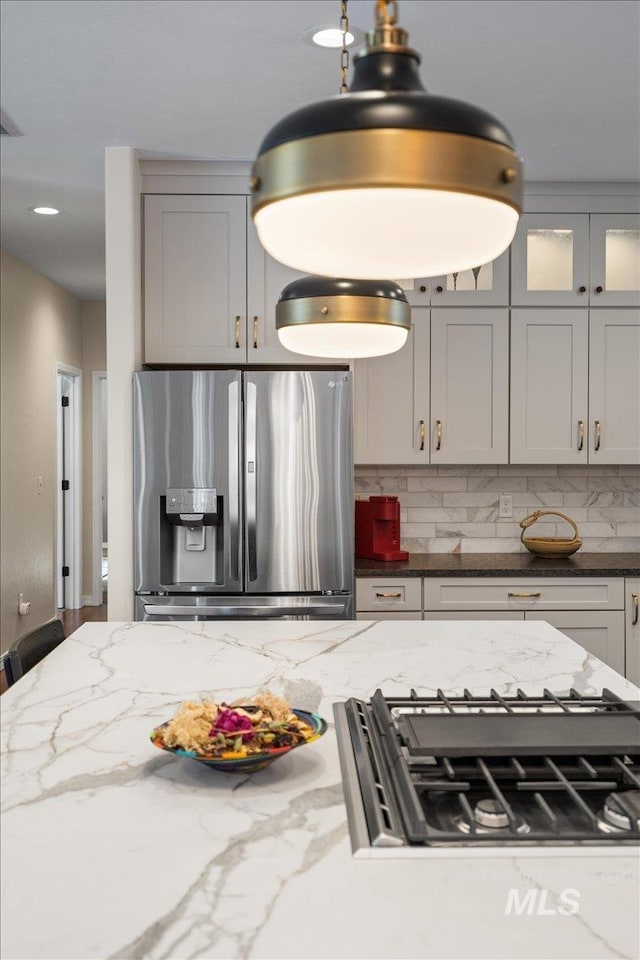 kitchen featuring backsplash, gray cabinets, light stone counters, and stainless steel appliances