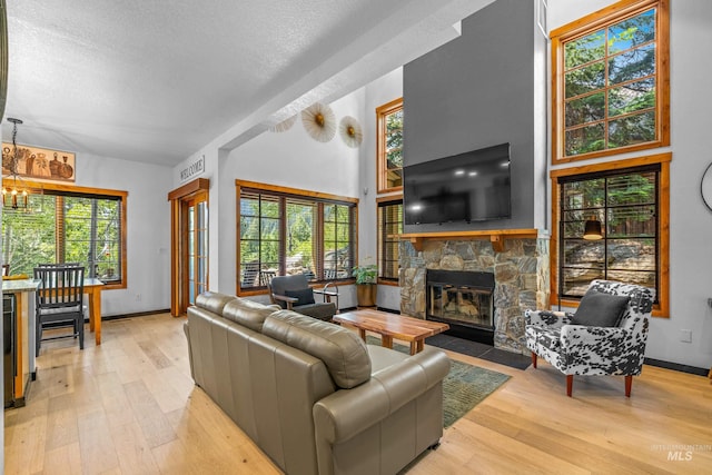 7 Golden Bench Ct, Donnelly, ID 83615 - living area featuring a stone fireplace, vaulted ceiling, light wood-style floors, a chandelier, and plenty of natural light
