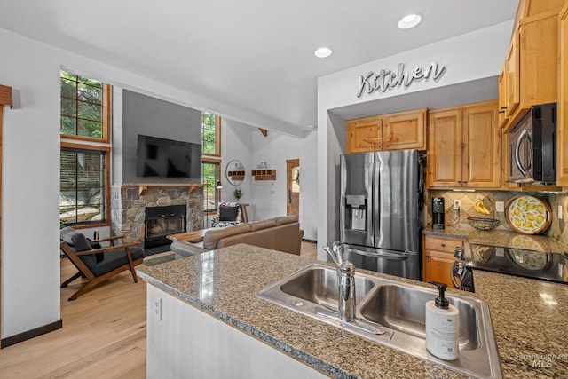 7 Golden Bench Ct, Donnelly, ID 83615 - kitchen with stainless steel refrigerator with ice dispenser, open floor plan, backsplash, a stone fireplace, and light wood-style floors