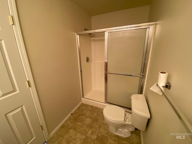 bathroom with tile patterned flooring, a shower with door, and toilet