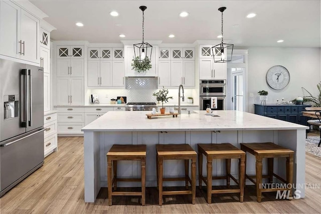 kitchen featuring stainless steel appliances, a large island, and decorative light fixtures