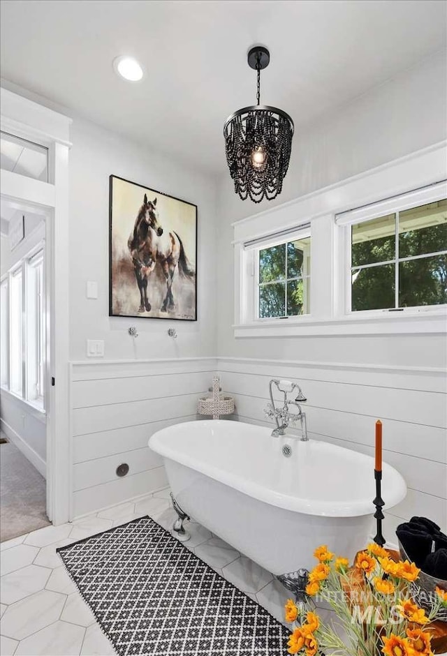 bathroom with an inviting chandelier and a bath