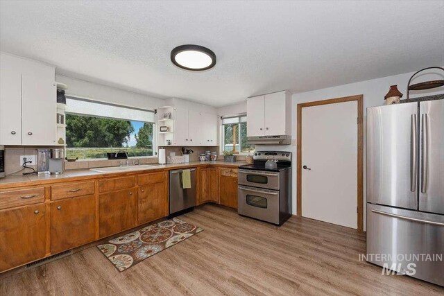 kitchen with sink, stainless steel appliances, light hardwood / wood-style floors, and white cabinets