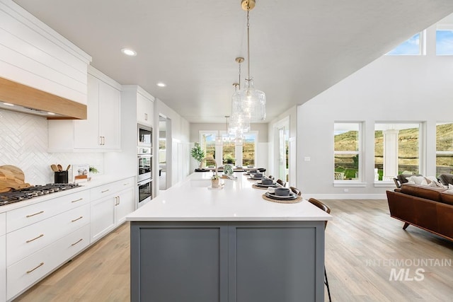 kitchen with white cabinets, light countertops, stainless steel appliances, open floor plan, and backsplash