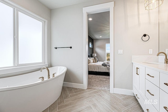 ensuite bathroom with baseboards, a soaking tub, vanity, and ensuite bath