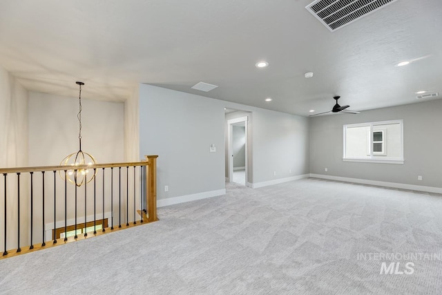 carpeted empty room featuring baseboards, ceiling fan with notable chandelier, recessed lighting, and visible vents