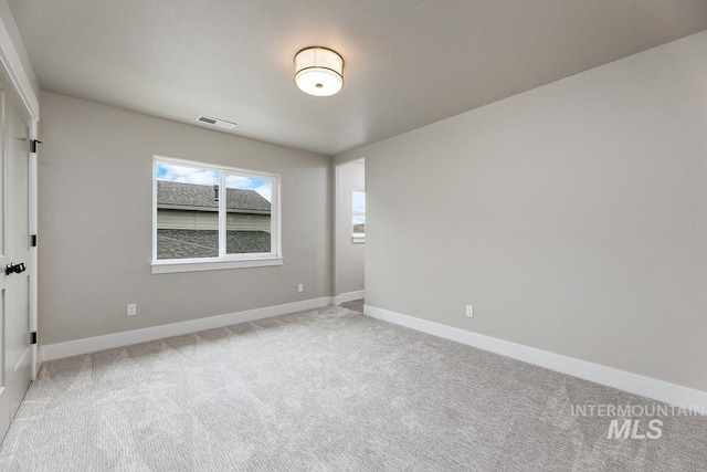 empty room featuring baseboards, light carpet, and visible vents