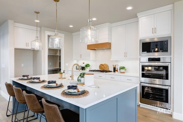 kitchen featuring white cabinets, light countertops, built in microwave, and double oven
