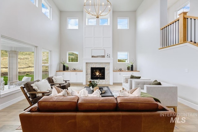 living area featuring baseboards, a wealth of natural light, a notable chandelier, and a towering ceiling