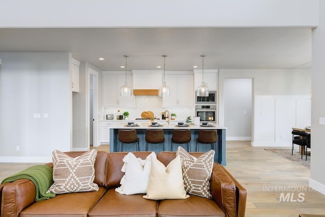 kitchen with light wood-style floors, light countertops, white cabinets, and stainless steel oven