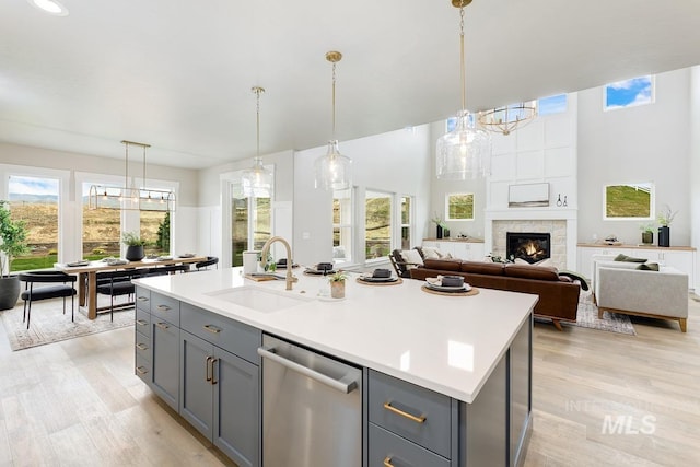 kitchen featuring a sink, light wood finished floors, light countertops, stainless steel dishwasher, and gray cabinetry
