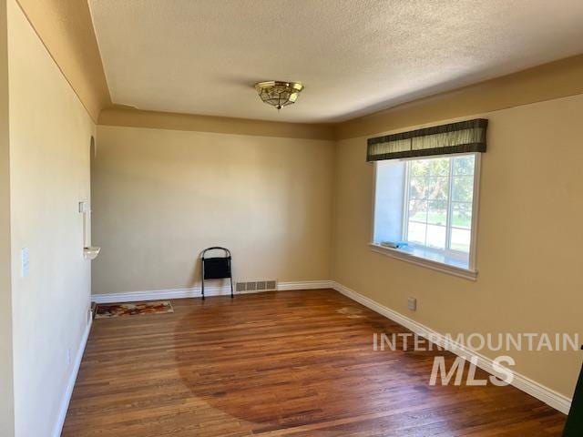 empty room with visible vents, baseboards, and wood finished floors