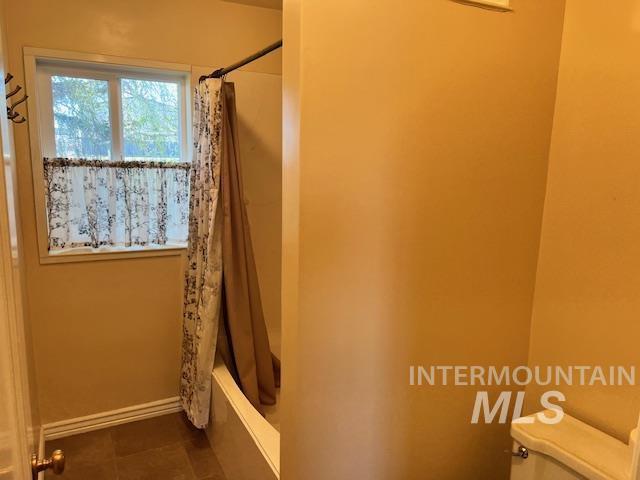 bathroom with shower / bath combo, baseboards, and tile patterned floors