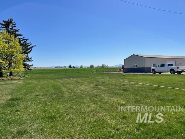 view of yard featuring a rural view, an outdoor structure, and a pole building