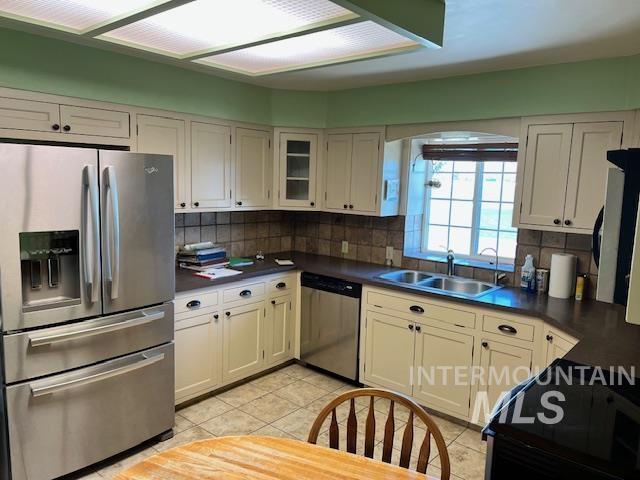 kitchen with a sink, decorative backsplash, appliances with stainless steel finishes, and dark countertops