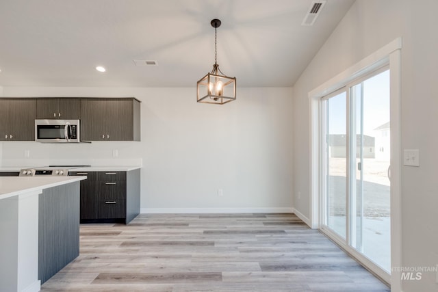 7308 E Marble Springs Dr, Nampa, ID 83687 - kitchen with hanging light fixtures, stainless steel microwave, light wood-style floors, light countertops, and visible vents
