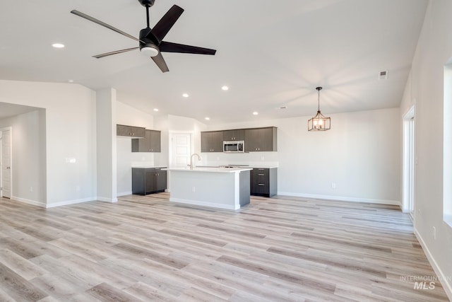 7308 E Marble Springs Dr, Nampa, ID 83687 - unfurnished living room featuring recessed lighting, light wood-style flooring, vaulted ceiling, ceiling fan with notable chandelier, and a sink