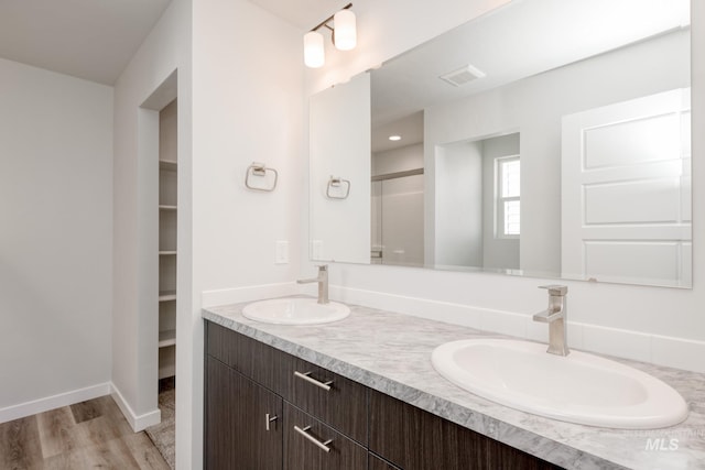 7308 E Marble Springs Dr, Nampa, ID 83687 - bathroom with wood finished floors, a shower with door, double vanity, and a sink