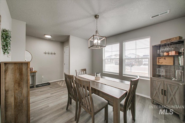 dining room with visible vents, baseboards, a chandelier, and light wood finished floors