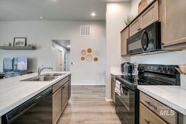 kitchen with black appliances, light countertops, visible vents, and a sink