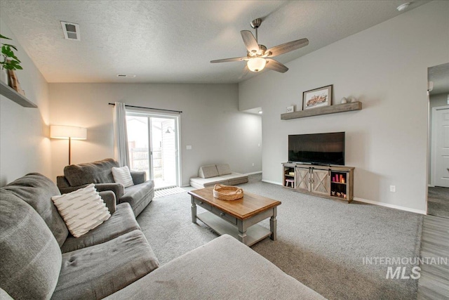 living room featuring a ceiling fan, baseboards, lofted ceiling, a textured ceiling, and carpet flooring