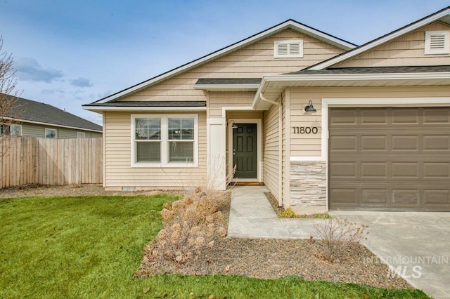 bungalow featuring stone siding, fence, concrete driveway, a front yard, and a garage