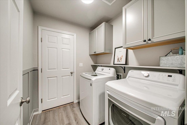 washroom featuring cabinet space, light wood-style floors, and washing machine and dryer