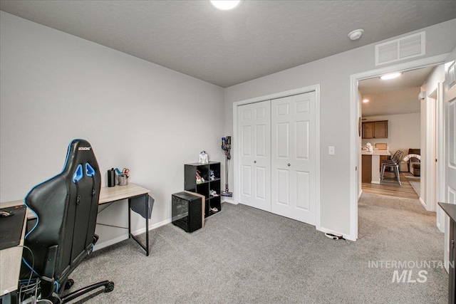 office space featuring visible vents, carpet floors, a textured ceiling, and baseboards