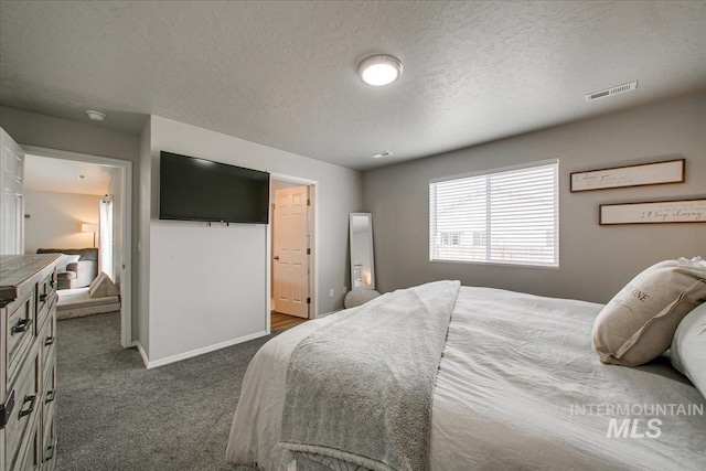 bedroom featuring visible vents, baseboards, a textured ceiling, and dark carpet