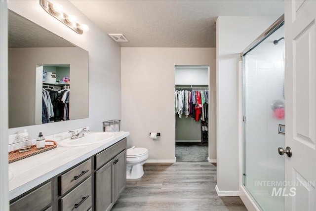 bathroom featuring visible vents, wood finished floors, a stall shower, and vanity