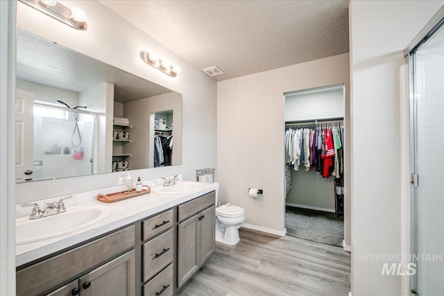 full bathroom with double vanity, visible vents, wood finished floors, and a sink