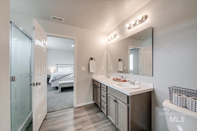 ensuite bathroom featuring a sink, visible vents, and a shower stall