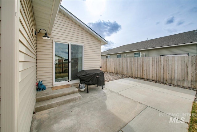 view of patio with area for grilling, entry steps, and fence