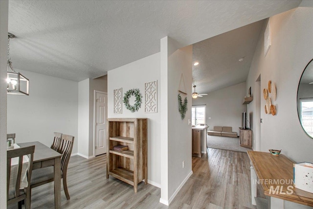 dining space featuring ceiling fan, baseboards, a textured ceiling, and light wood-style flooring