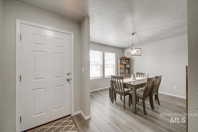 dining room with an inviting chandelier, wood finished floors, baseboards, and a textured ceiling