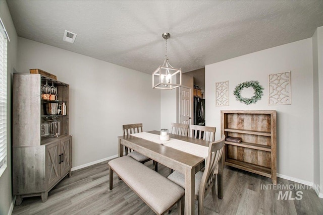 dining room with a notable chandelier, visible vents, light wood-type flooring, and baseboards