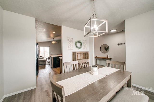 dining space featuring a chandelier, baseboards, light wood finished floors, and a textured ceiling