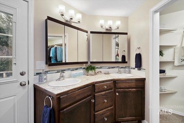 bathroom featuring a walk in closet, a sink, decorative backsplash, and double vanity