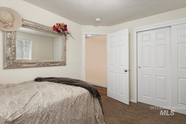 carpeted bedroom featuring a textured ceiling, a closet, and baseboards