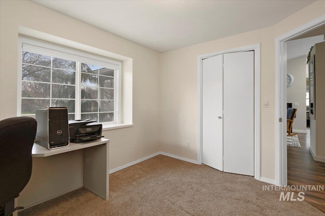 carpeted office space featuring plenty of natural light and baseboards